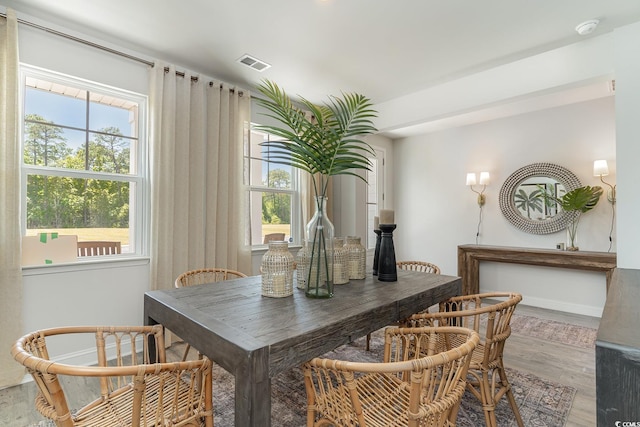 dining room featuring plenty of natural light, baseboards, light wood finished floors, and visible vents