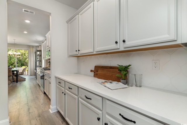 bar with backsplash, visible vents, appliances with stainless steel finishes, light wood-style floors, and recessed lighting