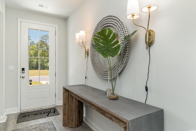 doorway with baseboards, wood finished floors, and visible vents