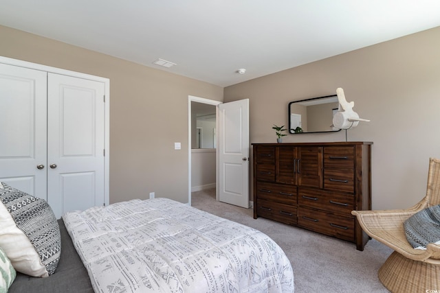 bedroom featuring baseboards, visible vents, light carpet, and a closet