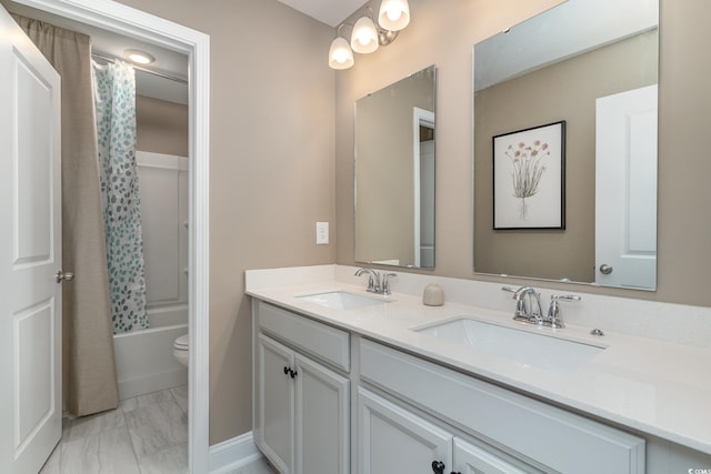 bathroom with a sink, toilet, double vanity, and marble finish floor