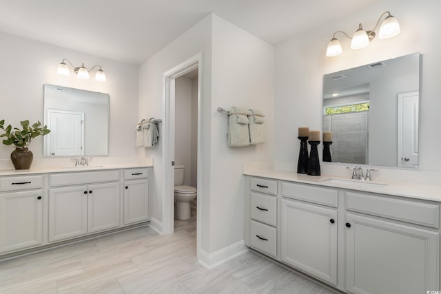 full bath featuring visible vents, a sink, baseboards, and two vanities