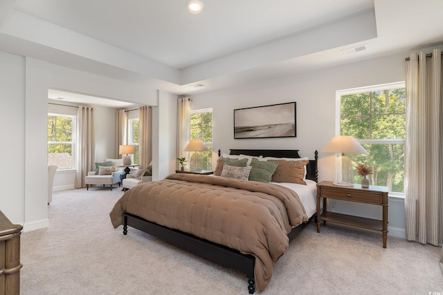 bedroom with visible vents, baseboards, multiple windows, and light carpet