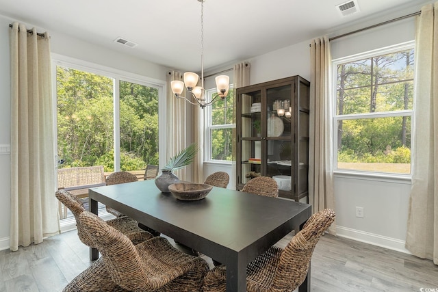 dining space featuring baseboards, a notable chandelier, light wood-type flooring, and visible vents