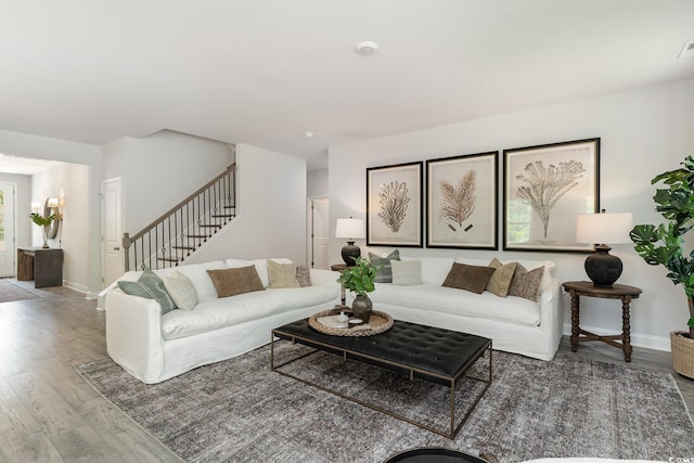 living room featuring stairway, baseboards, and wood finished floors