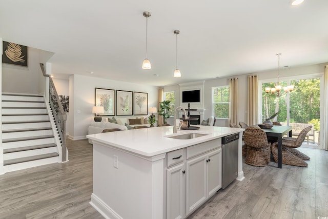 kitchen with stainless steel dishwasher, open floor plan, a chandelier, and a sink