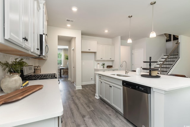 kitchen with a sink, appliances with stainless steel finishes, white cabinets, and light wood-style flooring
