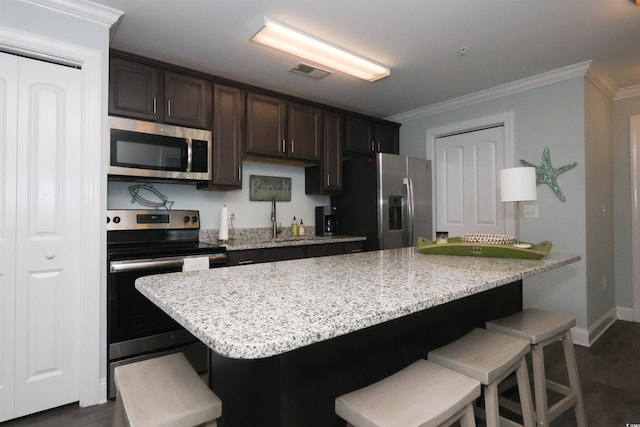 kitchen with dark wood-style flooring, appliances with stainless steel finishes, visible vents, and a kitchen bar