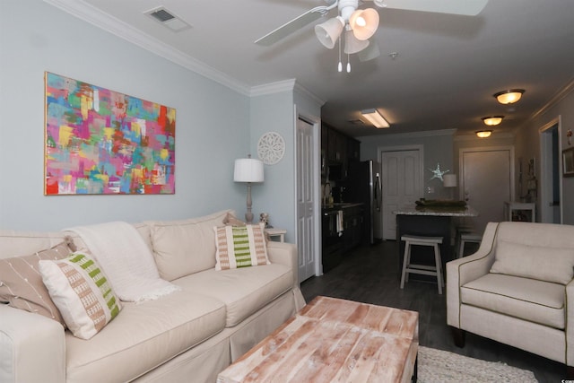 living room featuring visible vents, ornamental molding, dark wood-type flooring, and a ceiling fan