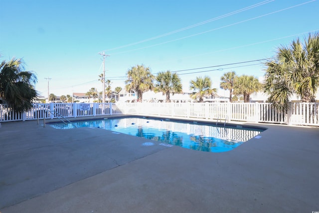 pool with a patio area and fence