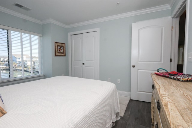 bedroom with visible vents, crown molding, dark wood finished floors, baseboards, and a closet