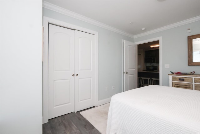 bedroom with a closet, ornamental molding, dark wood-style flooring, and baseboards
