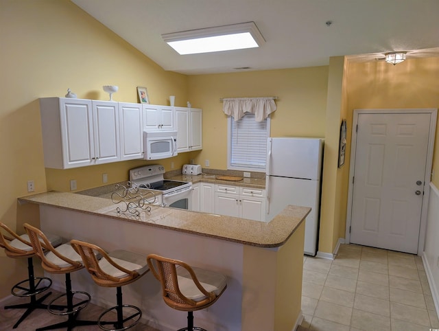 601 Hillside Dr N Unit 2245, North Myrtle Beach, SC 29582 - kitchen featuring white appliances, a peninsula, a kitchen breakfast bar, white cabinetry, and light tile patterned floors