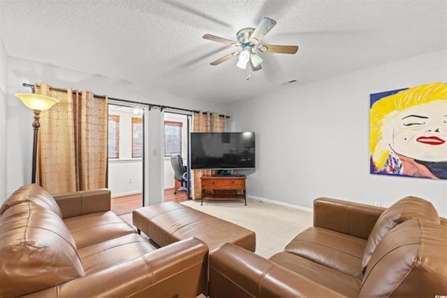 living room with a textured ceiling, baseboards, a ceiling fan, and visible vents