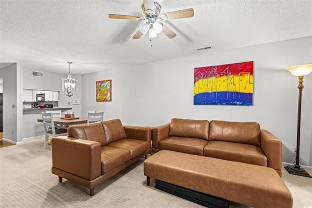 living room featuring a textured ceiling, visible vents, light colored carpet, and ceiling fan with notable chandelier