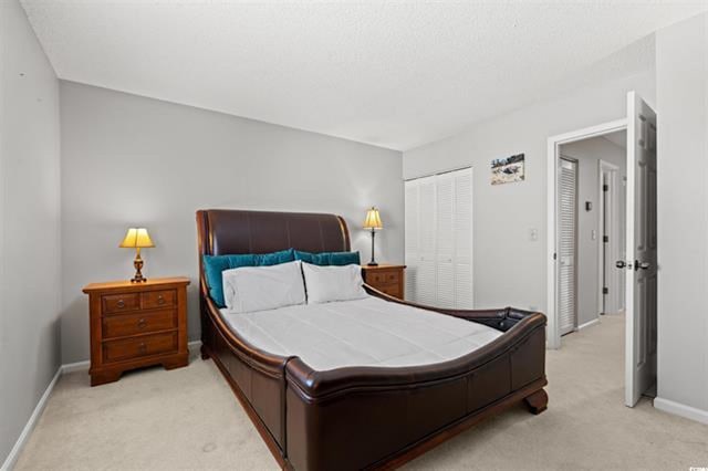bedroom featuring light carpet, a closet, and baseboards