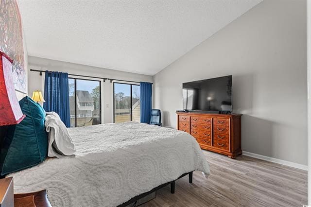 bedroom featuring lofted ceiling, access to outside, baseboards, and wood finished floors