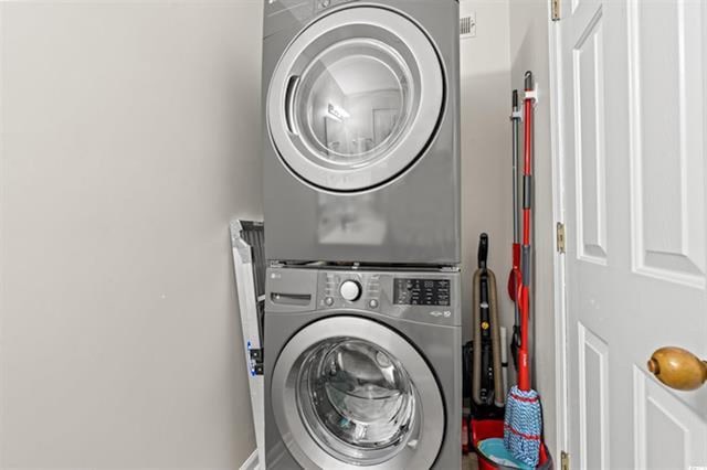 clothes washing area with laundry area and stacked washer and clothes dryer