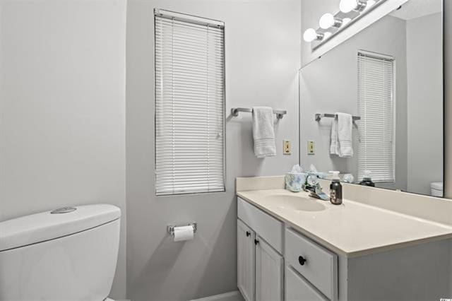 bathroom featuring toilet, baseboards, and vanity
