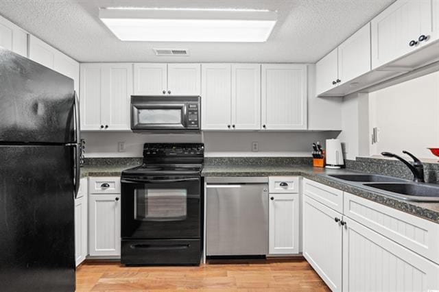 kitchen with a sink, light wood-style flooring, black appliances, and visible vents