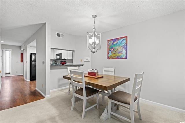 dining room with carpet flooring, a textured ceiling, visible vents, baseboards, and a chandelier