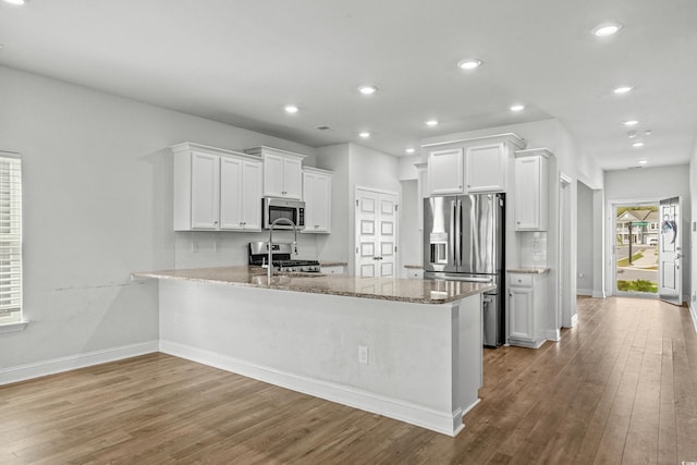 852 Harrison Mill St, Myrtle Beach, SC 29579 - kitchen featuring appliances with stainless steel finishes, wood finished floors, light stone countertops, white cabinetry, and recessed lighting