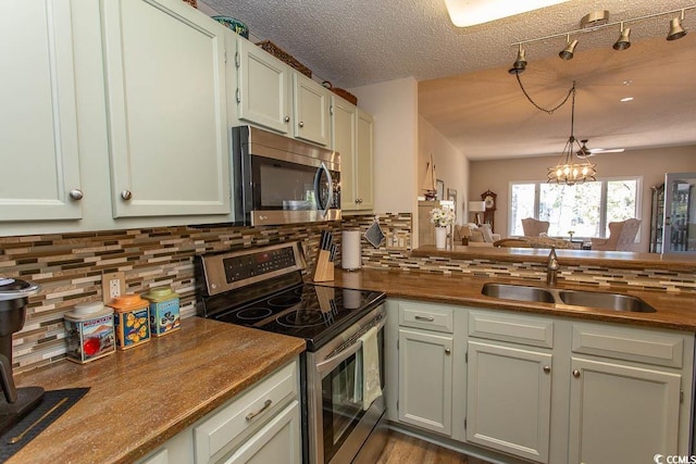 1221 Tidewater Dr Unit 1922, North Myrtle Beach, SC 29582 - kitchen featuring appliances with stainless steel finishes, a sink, decorative backsplash, decorative light fixtures, and a textured ceiling