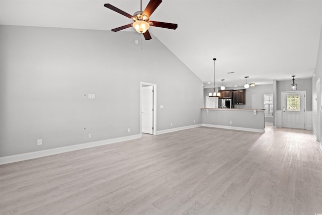 unfurnished living room with baseboards, high vaulted ceiling, light wood-style floors, and a ceiling fan