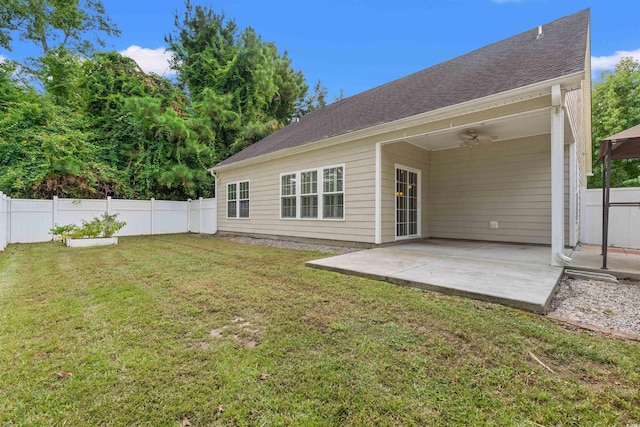 rear view of property with roof with shingles, a patio, a fenced backyard, ceiling fan, and a yard