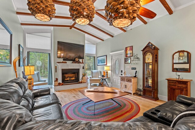 living area with beamed ceiling, ceiling fan, high vaulted ceiling, a fireplace with raised hearth, and light wood-style flooring