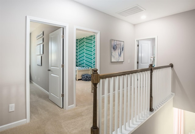 corridor featuring light carpet, baseboards, and an upstairs landing