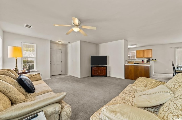 living room with light carpet, baseboards, visible vents, and a ceiling fan