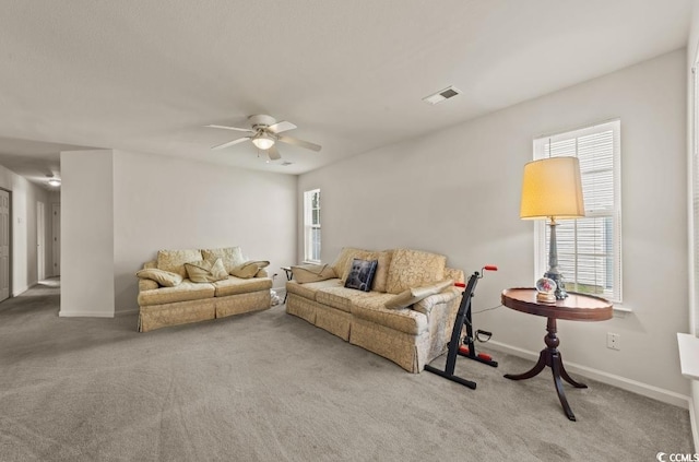 carpeted living area with baseboards, visible vents, and ceiling fan