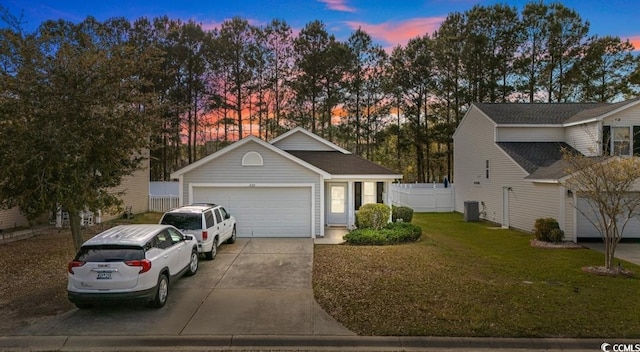 view of front of house featuring concrete driveway, cooling unit, fence, an attached garage, and a lawn