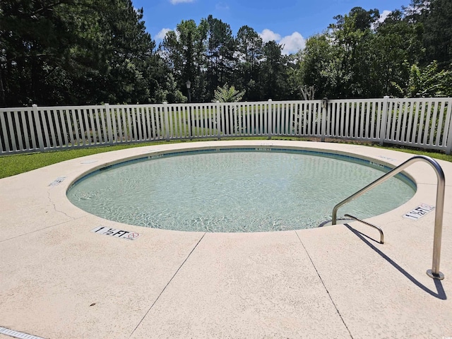 view of swimming pool with a patio area, a swimming pool, and fence