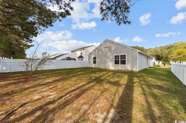 rear view of property featuring a fenced backyard and a yard