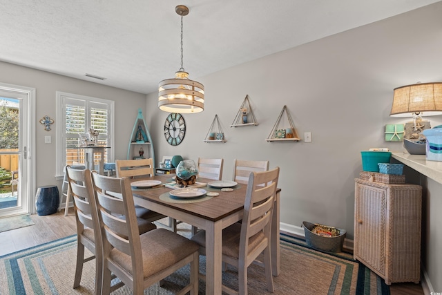 dining room featuring baseboards, visible vents, a textured ceiling, and wood finished floors