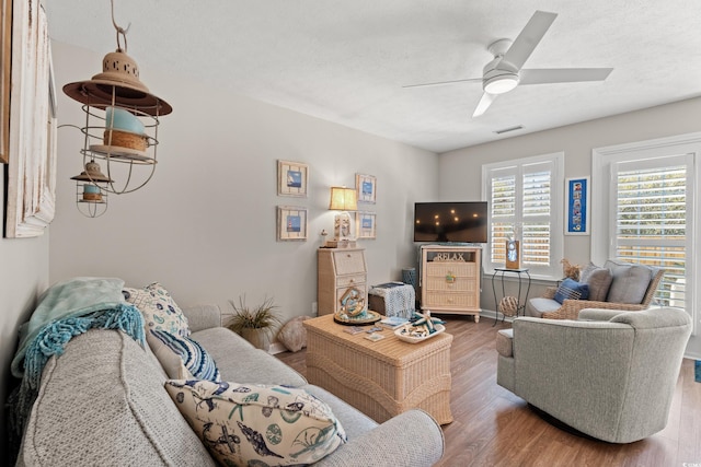 living area with a textured ceiling, visible vents, wood finished floors, and a ceiling fan