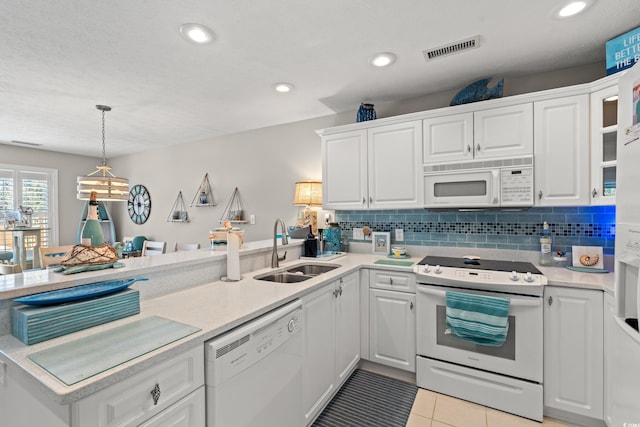 kitchen featuring light countertops, visible vents, a peninsula, white appliances, and a sink