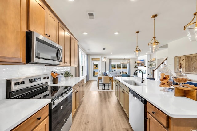 kitchen with appliances with stainless steel finishes, a sink, light wood-style floors, light countertops, and recessed lighting