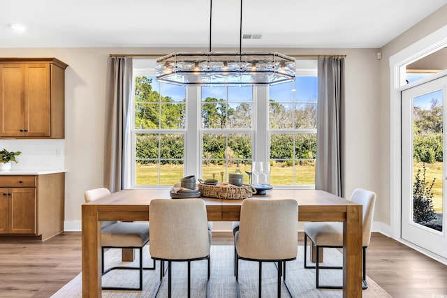 dining area with baseboards, a chandelier, wood finished floors, and visible vents