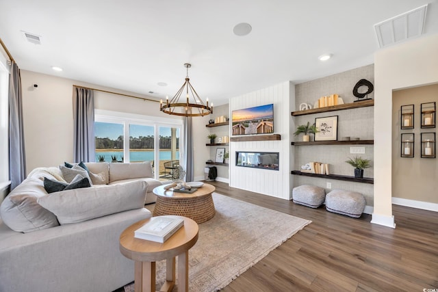 living room with a chandelier, wood finished floors, baseboards, recessed lighting, and a large fireplace
