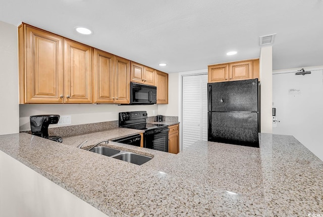 kitchen featuring a sink, visible vents, light stone countertops, and black appliances