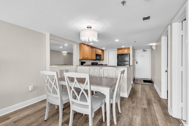 dining area featuring baseboards, visible vents, light wood-style floors, and an inviting chandelier