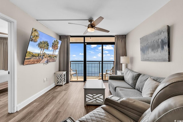 living room with baseboards, floor to ceiling windows, wood finished floors, and ceiling fan