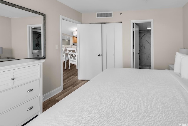 bedroom with connected bathroom, a closet, dark wood finished floors, baseboards, and visible vents