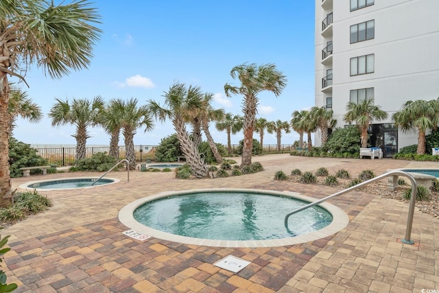 view of swimming pool with a community hot tub, a patio area, fence, and a pool