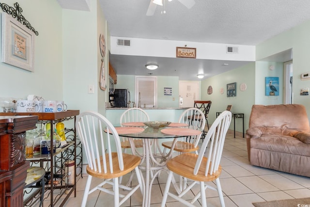 dining space featuring visible vents, a ceiling fan, a textured ceiling, and light tile patterned floors
