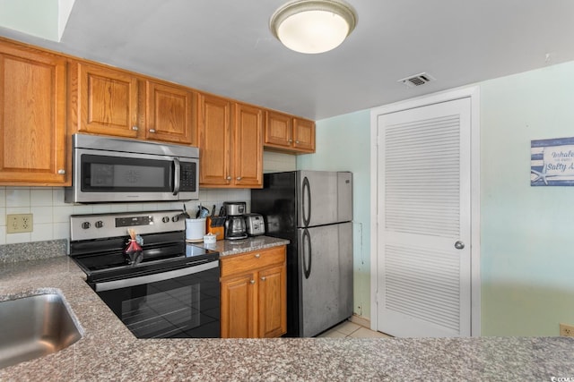 kitchen featuring a sink, stainless steel appliances, decorative backsplash, light tile patterned floors, and visible vents