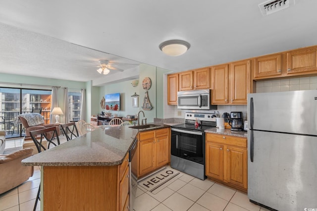 kitchen featuring visible vents, a sink, a peninsula, stainless steel appliances, and light tile patterned flooring